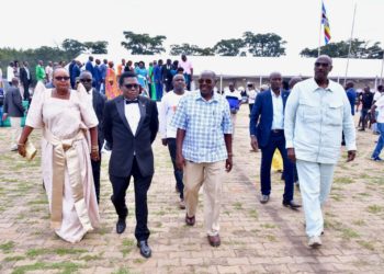 DP President Norbert Mao (in black suit), walks to the podium at his homecoming in Gulu City, escorted by (L-R): Ms Lydia Wanyoto of NRM Women's League, NRM deputy supremo Al-hajj Moses Kigongo, and President Museveni's brother, Gen Salim Saleh.