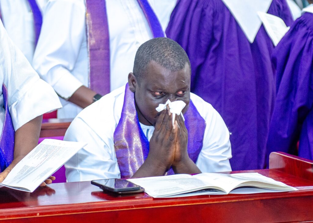 Sembene Oculi breaks down during the funeral service.